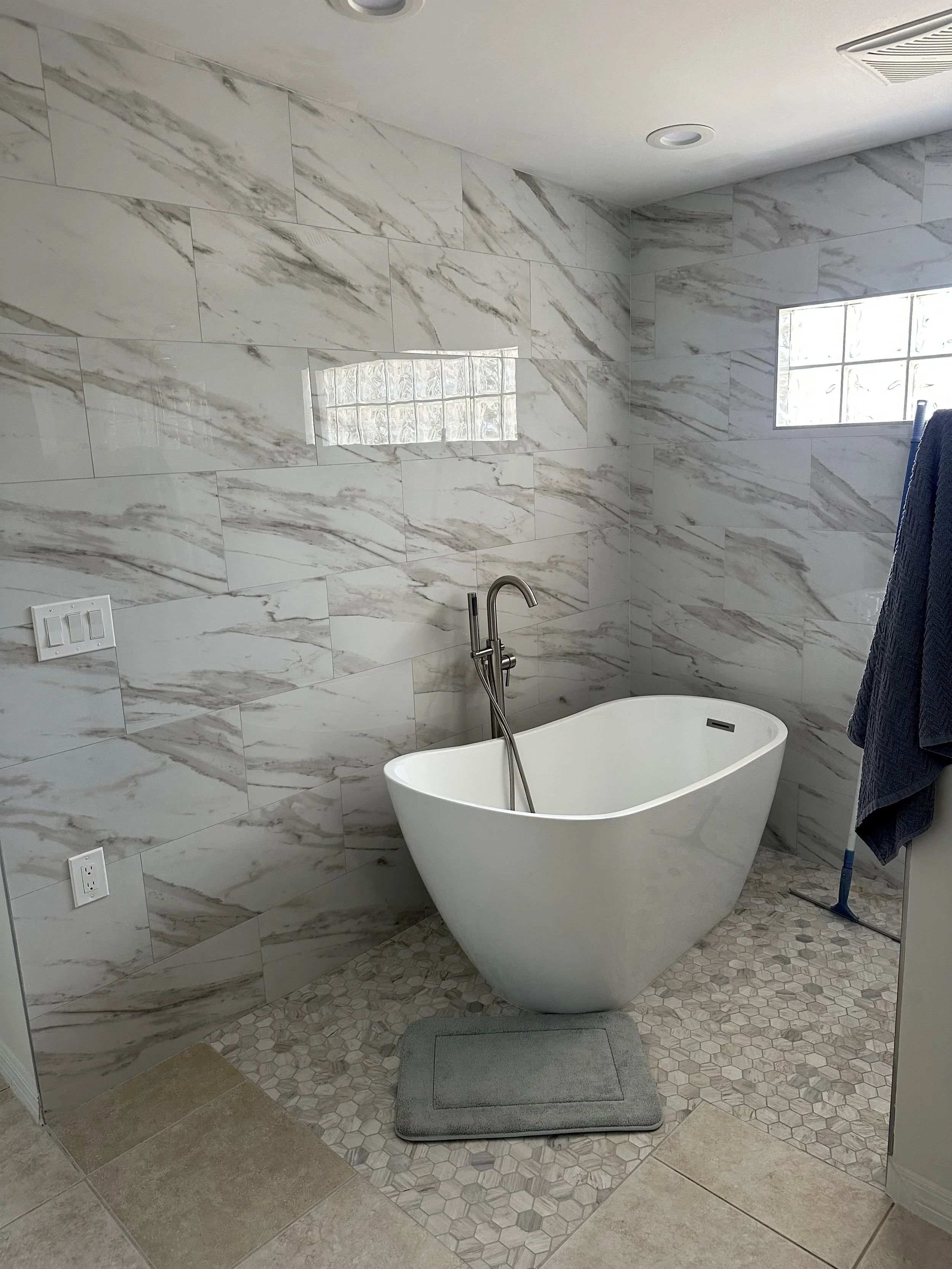 Luxury bathroom remodel with marble tile walls and freestanding soaking tub